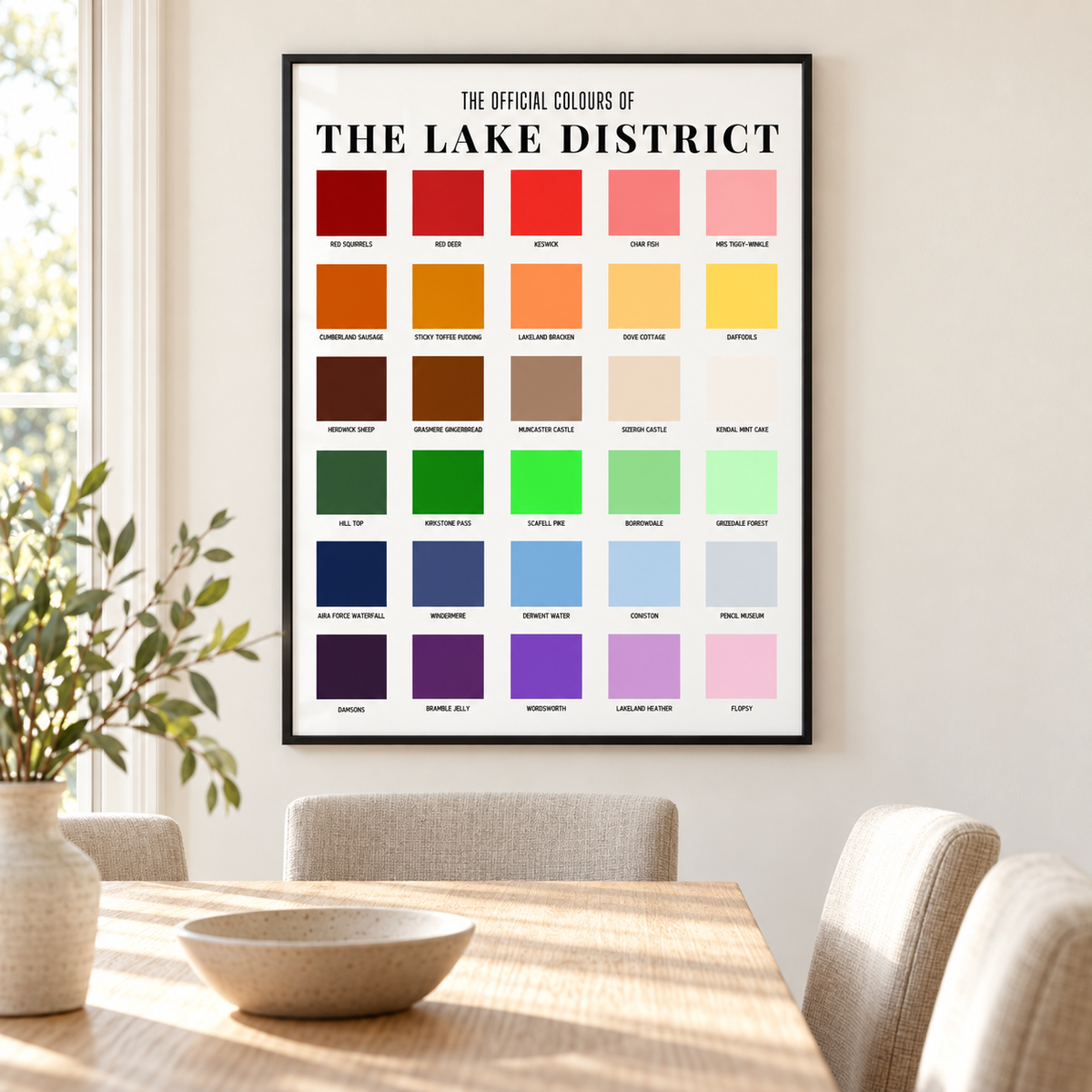 Lake District wall art in a thin black frame above an oak dining table, displaying colour squares inspired by Cumbrian places, wildlife and food.