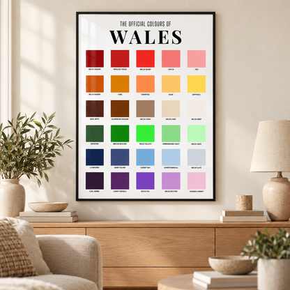 
Wales colour chart print in a thin black frame above an oak sideboard in a neutral lounge, featuring 30 colourful squares with Welsh-themed labels.