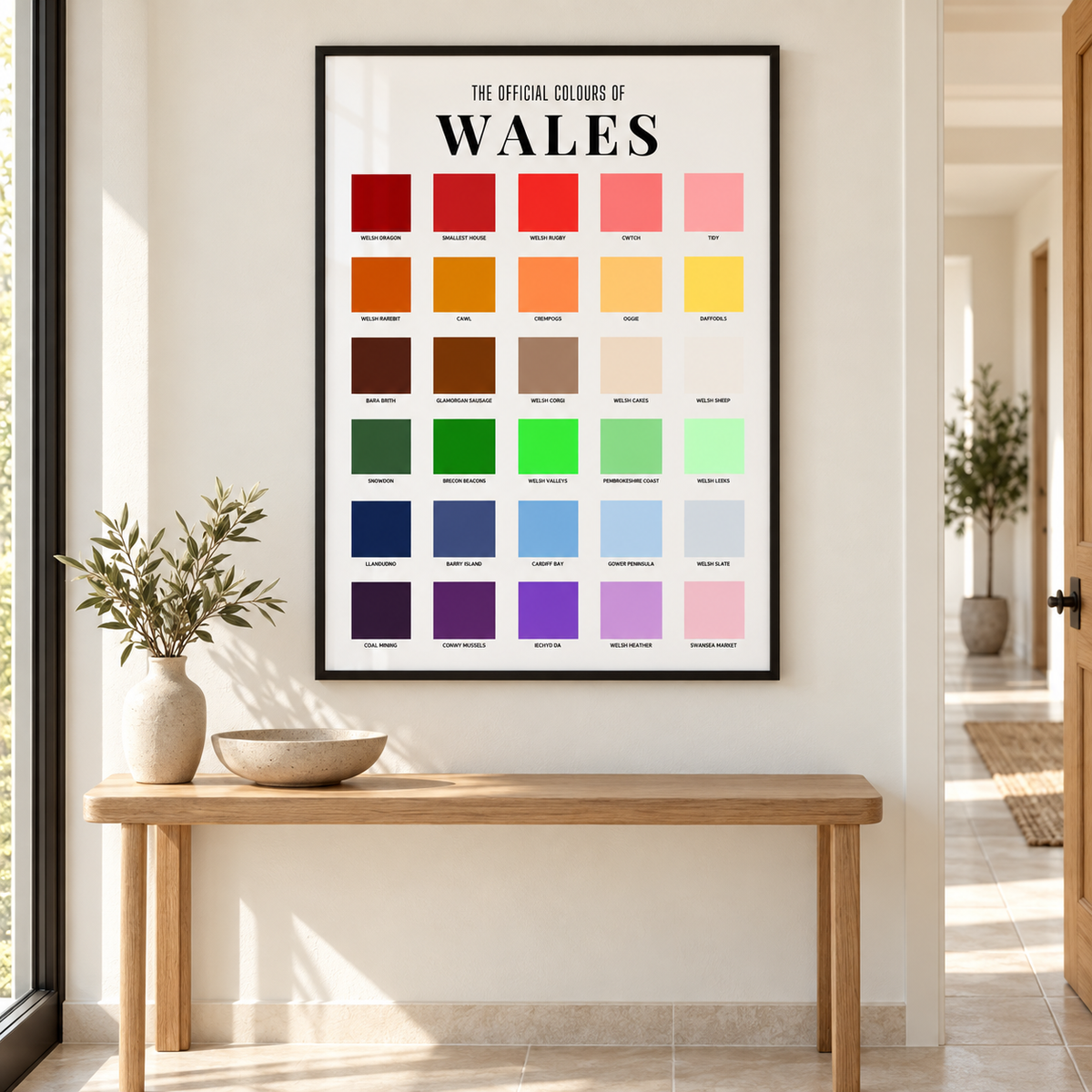 Welsh colour chart wall art in a thin black portrait frame above an oak console in a bright hallway, featuring Welsh places, foods, symbols and sayings.