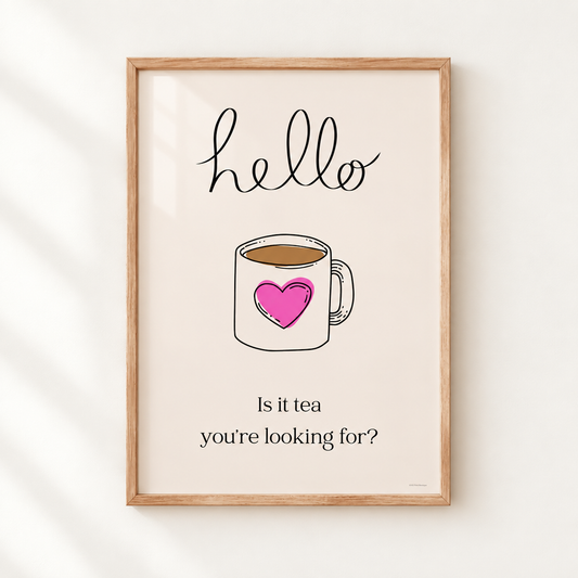 A framed typographic art print featuring a hand-drawn coffee mug with a pink heart, the word 'hello' at the top, and the phrase 'Is it tea you're looking for?' at the bottom, shown hanging on a light wall.