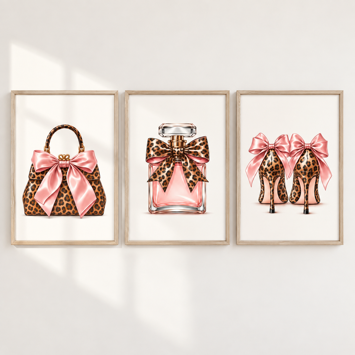 Three framed fashion illustrations on a white wall: a leopard-print handbag with a pink satin bow, a pink perfume bottle with a leopard-print bow, and a pair of pink high heels with leopard-print bows.