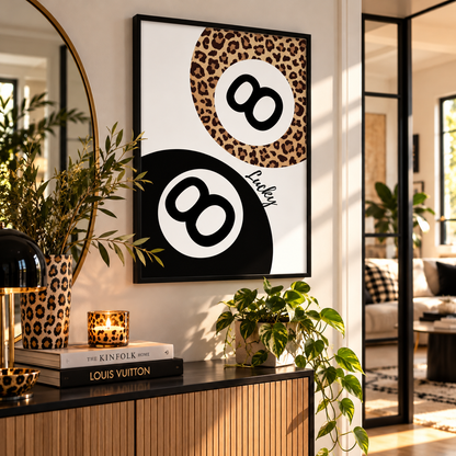 A framed wall art print featuring two stylized billiard 8-ball designs in leopard print and black-and-white, displayed in a modern living room setting above a console table with books and plants.