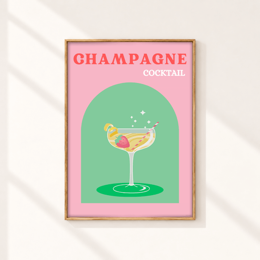 A framed art print featuring a retro-style illustration of a champagne cocktail on a pink background with the text 'CHAMPAGNE COCKTAIL' in coral and white lettering. The print is housed in a light wood frame and displayed on a warm off-white wall with soft diagonal shadows.