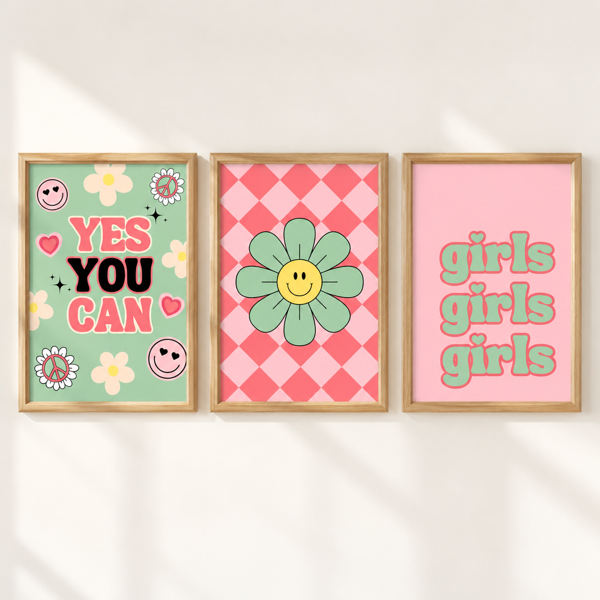 Three framed retro-style art prints hanging side-by-side on a white wall with soft shadows. The left print has a mint green background with the text 'YES YOU CAN' in pink and black, decorated with smiley faces and flowers.