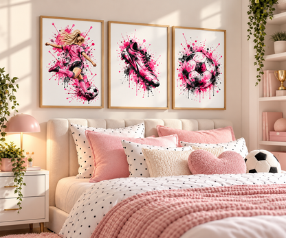 A styled bedroom scene with three framed wall art prints above a bed. The prints feature pink and black watercolor-style illustrations of a soccer player, a soccer cleat, and a soccer ball on white backgrounds with gold frames.