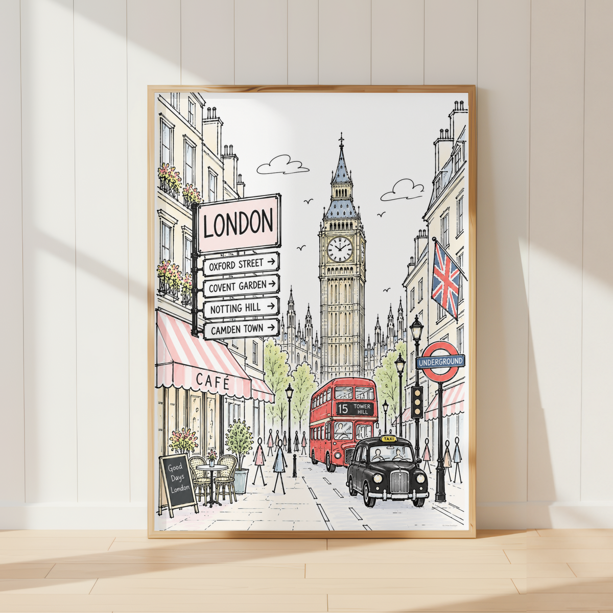 A framed London street art print leaning against a white paneled wall on a light wood floor. The illustration shows Big Ben, a red double-decker bus, a black cab, storefronts, and street signs, with the word LONDON visible on a sign.