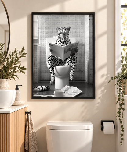 A framed black and white art print of a leopard reading a newspaper on a toilet, displayed on a beige wall above a white toilet in a modern bathroom setting.