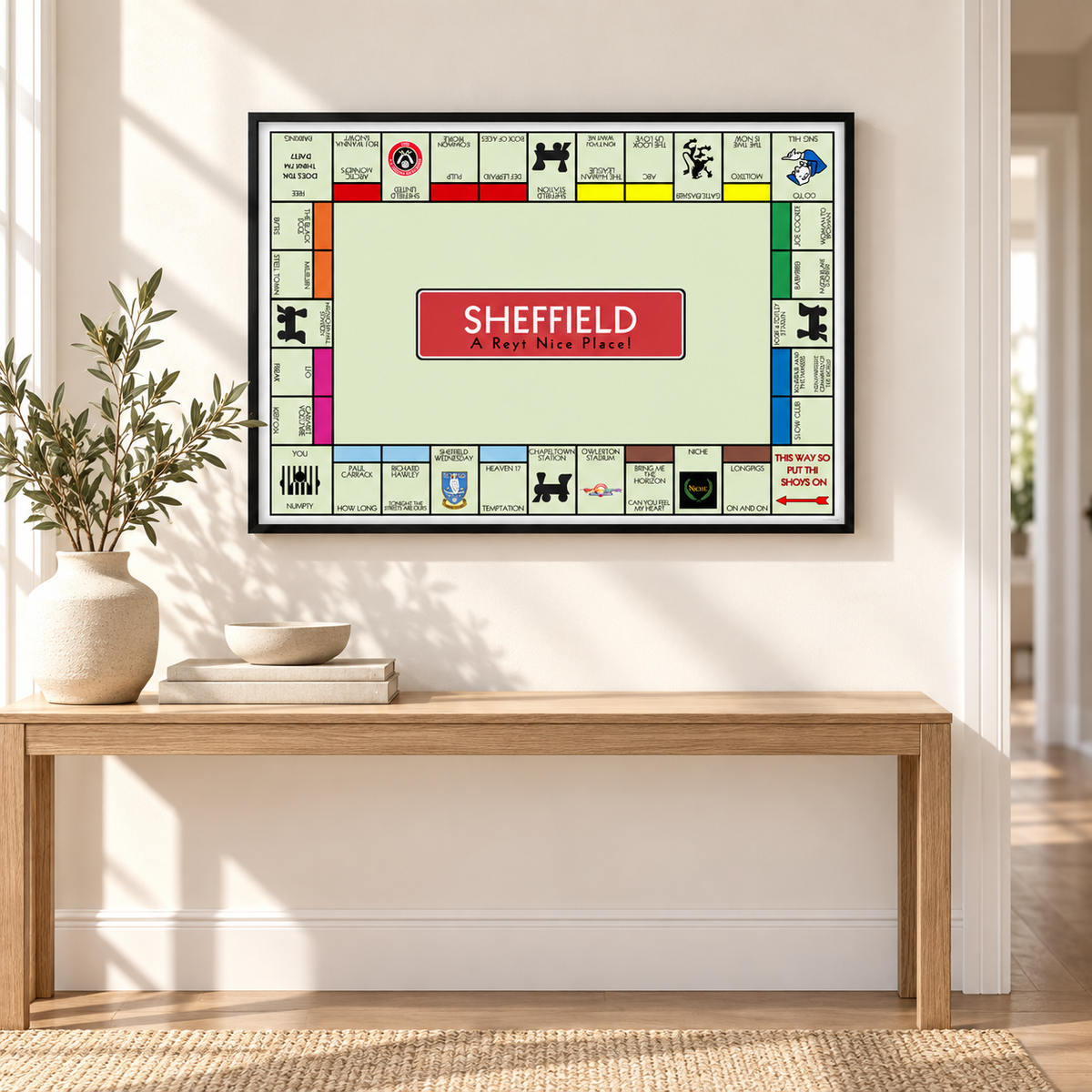 Sheffield Monopoly-style wall art in a black landscape frame above an oak console table in a bright hallway, featuring music, football and local culture.