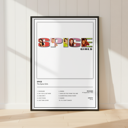 A framed Spice Girls 'Spice' music poster leaning against a white paneled wall on a light wood floor, with soft sunlight casting shadows across the scene.
