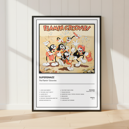 A framed music poster for 'Flamin' Groovies' featuring classic cartoon flamers and tracklist details, displayed on a light wood floor against a white paneled wall.