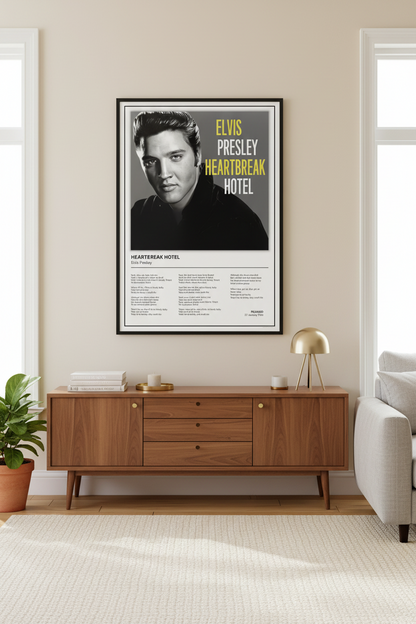 A framed Elvis Presley 'Heartbreak Hotel' poster leaning against a light beige paneled wall on a pale wood floor. The poster features a black-and-white portrait of Elvis, large yellow text reading 'ELVIS PRESLEY HEARTBREAK HOTEL,' and song lyrics printed below.