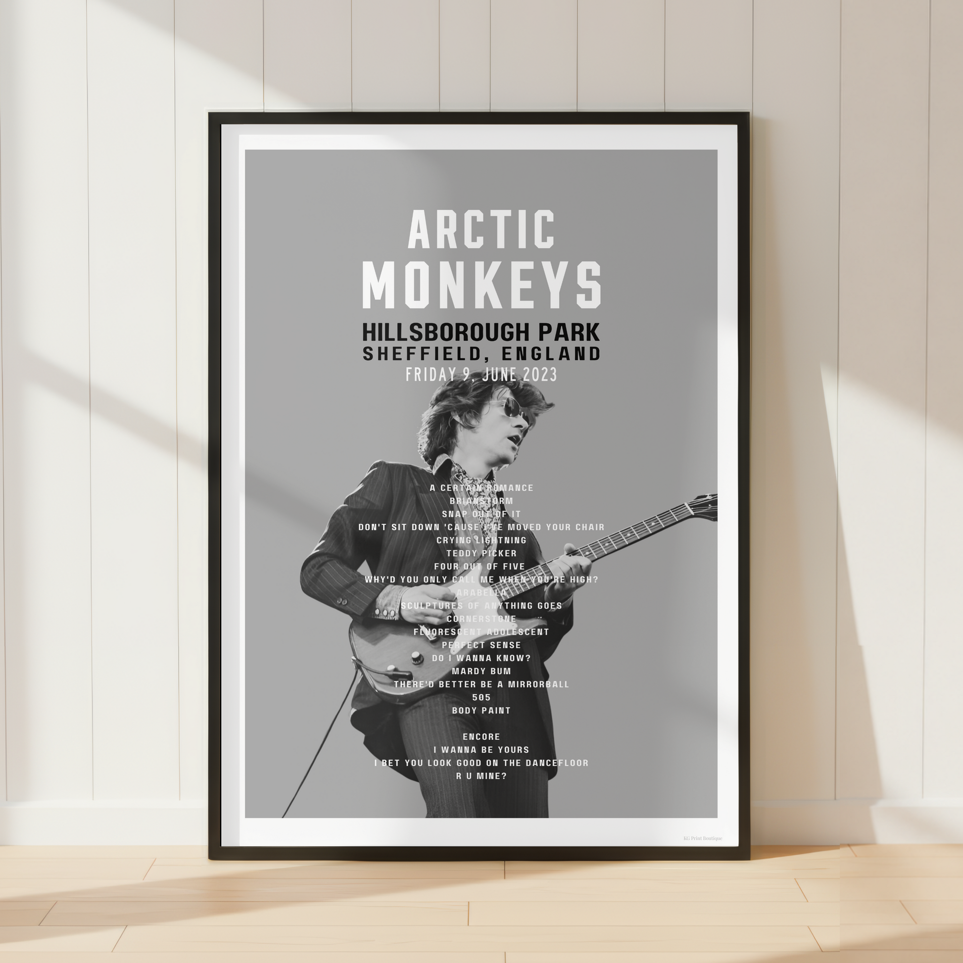 Premium Arctic Monkeys concert poster print showcasing the Hillsborough Park 2023 setlist in a bright contemporary living room with vinyl records and modern interiors.