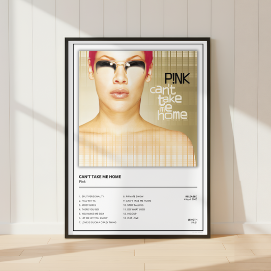 A framed music poster of Pink's 'Can't Take Me Home' leaning against a white paneled wall on a light wood floor, with soft window shadows cast across the scene.