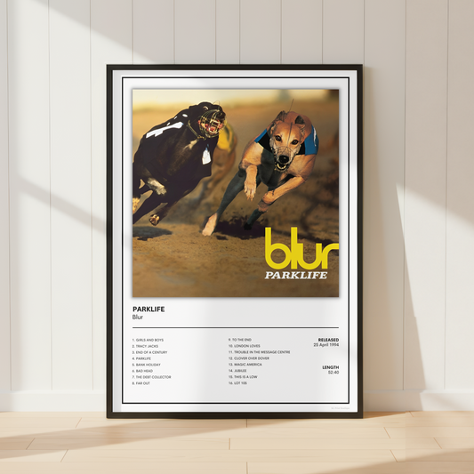 A framed Parklife music poster featuring a black-and-white racing dog scene with the band name 'blur' in yellow, leaning against a white paneled wall on a light wood floor.
