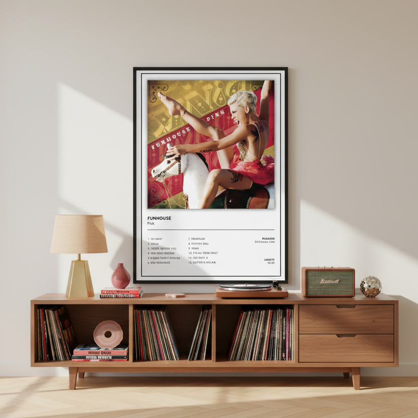 A framed music poster for Pink's album 'Funhouse' leaning against a white paneled wall on a light wood floor. The poster features a colorful album-cover style photo of Pink on a carousel, with the tracklist printed below on a white background.