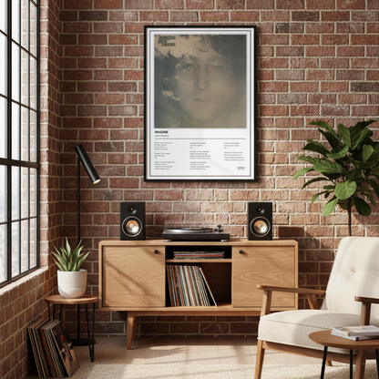 A framed John Lennon 'Imagine' poster leaning against a white paneled wall on a light wood floor, with soft sunlight casting shadows across the scene.
