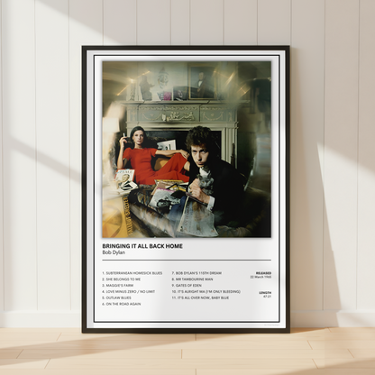 A framed music poster of Bill Dylan's 'Bringing It All Back Home' leaning against a white paneled wall on a light wood floor, with soft window shadows cast across the scene.