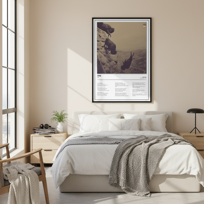 A framed art print featuring a sepia-toned photograph of three sheep on a rocky cliffside with printed text below, leaning against a white paneled wall on a light wood floor.