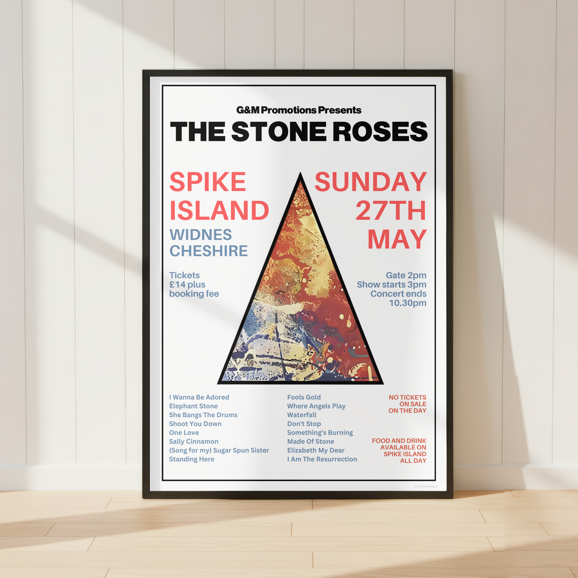 A framed concert poster for 'The Stone Roses' at Spike Island, displayed on a light wood floor against a white paneled wall with soft shadows.