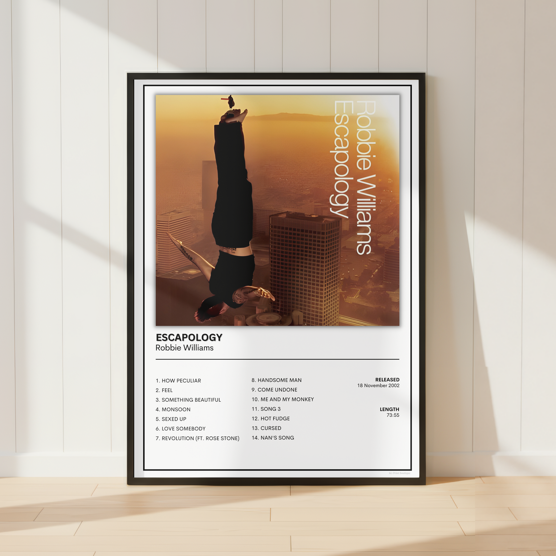 A framed music poster for Robbie Williams' album 'Escapology' leaning against a white paneled wall on a light wood floor, with soft window shadows cast across the scene.