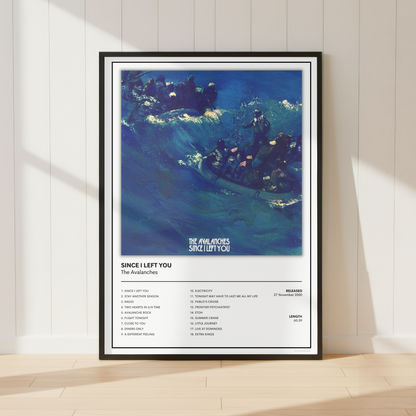 A framed music poster for The Avalanches' 'Since I Left You' leaning against a white paneled wall on a light wood floor. The poster features a blue-toned abstract wave illustration with the title text and a tracklist below.