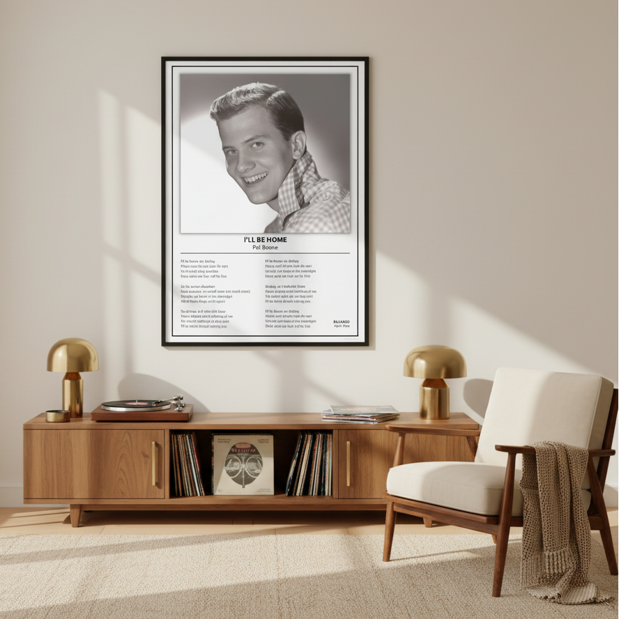 A framed black-and-white Pat Boone 'I'll Be Home' music poster is displayed leaning against a white paneled wall on a light wood floor, with soft window shadows cast across the scene.
