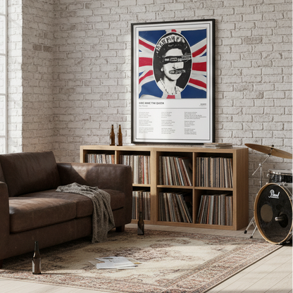 A framed music poster of Queen's 'God Save the Queen' leaning against a white paneled wall on a light wood floor, featuring a stylized portrait over a Union Jack background.