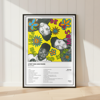 A framed music poster for De La Soul's '3 Feet High and Rising' leaning against a white paneled wall on a light wood floor.