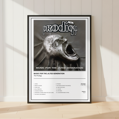 A framed music poster for the band Prodigy, featuring the album cover art for 'Music for the Jilted Generation' and a track list, leaning against a white paneled wall on a light wood floor.