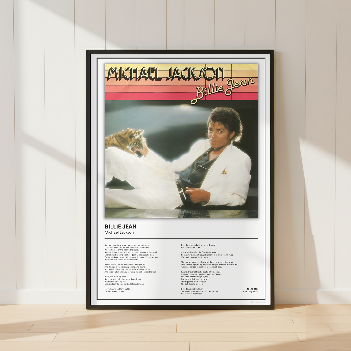 A framed Billie Jean Michael Jackson poster leaning against a white paneled wall on a light wood floor, with soft window shadows cast across the scene.