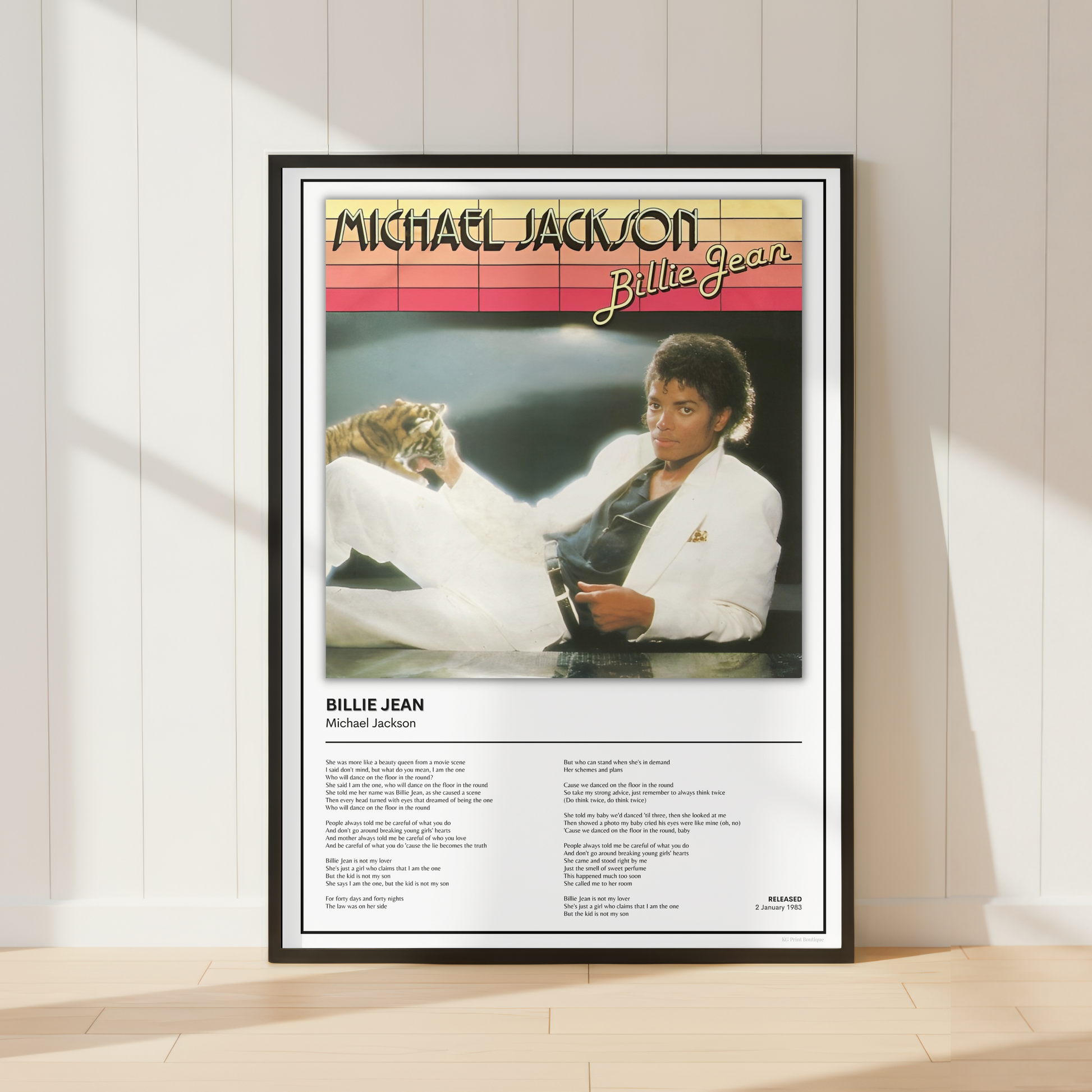 A framed Billie Jean Michael Jackson poster leaning against a white paneled wall on a light wood floor, with soft window shadows cast across the scene.