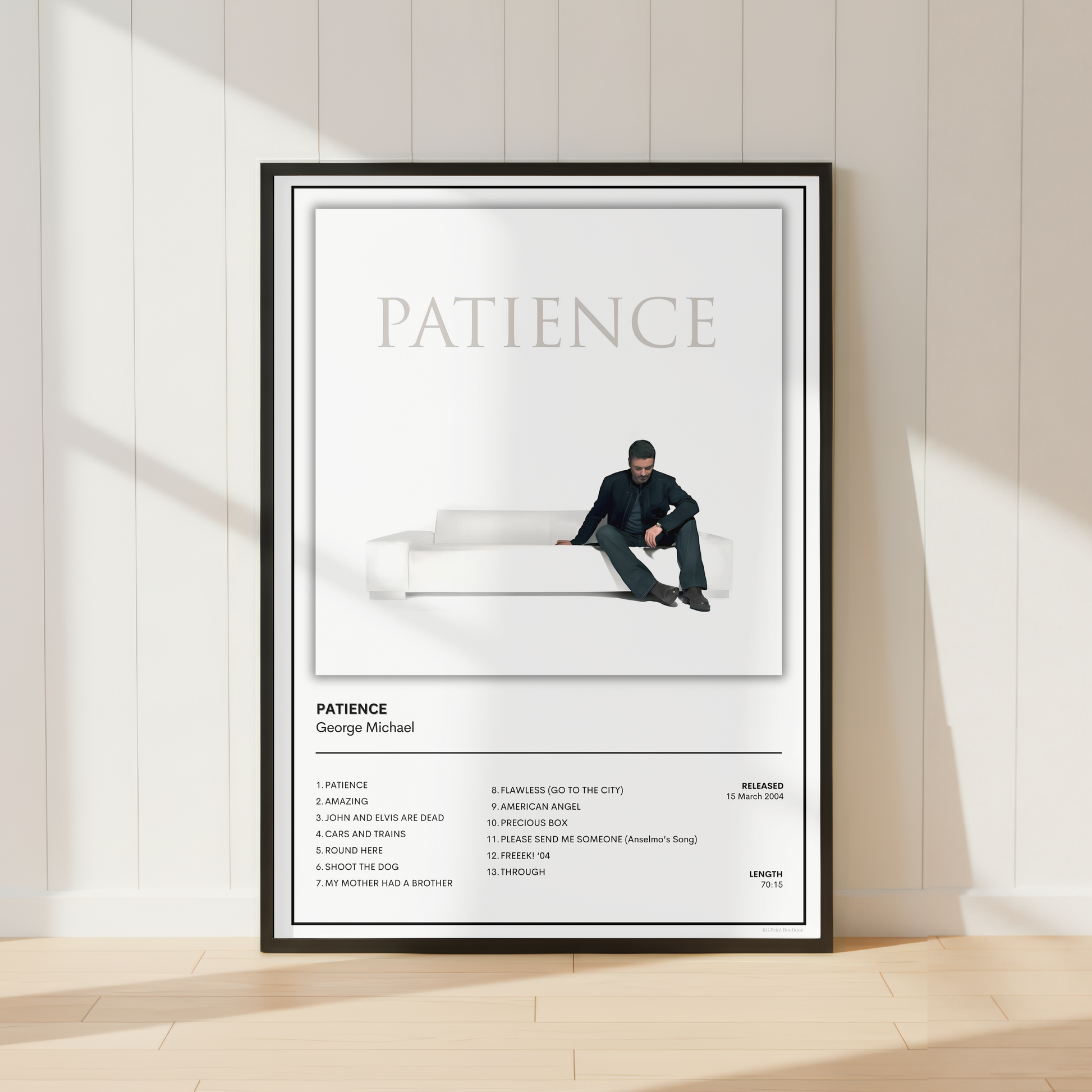 A framed minimalist music poster for George Michael's album 'Patience' leaning against a white paneled wall on a light wood floor, with soft window shadows cast across the scene.