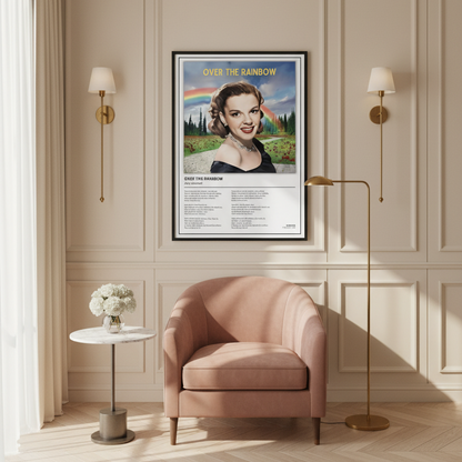 A framed poster of the classic movie song 'Over The Rainbow' by Judy Garland, leaning against a white paneled wall on a light wood floor. The poster features a vintage portrait of June Tabor with a rainbow in the background, and song lyrics printed below.