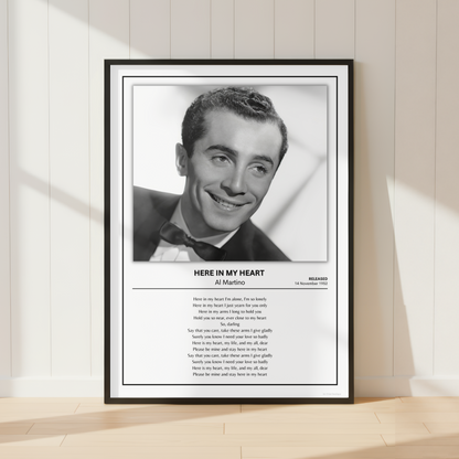 A framed black-and-white portrait print of Al Martino leaning against a light beige paneled wall on a pale wood floor. The print includes a black frame, white mat, the portrait, and printed text below reading 'HERE IN MY HEART' with 'Al Pacino' and 'Marilyn' visible.