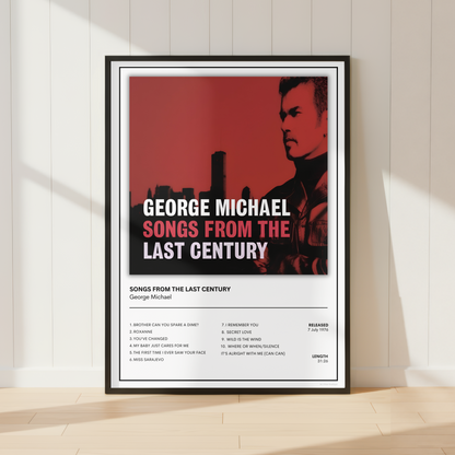 A framed music poster for George Michael's album 'Songs From The Last Century' leaning against a white paneled wall on a light wood floor, with soft sunlight casting shadows.