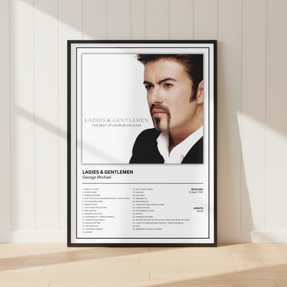 A framed music poster of George Michael's album 'Ladies & Gentlemen' leaning against a white paneled wall on a light wood floor, with soft sunlight casting shadows.