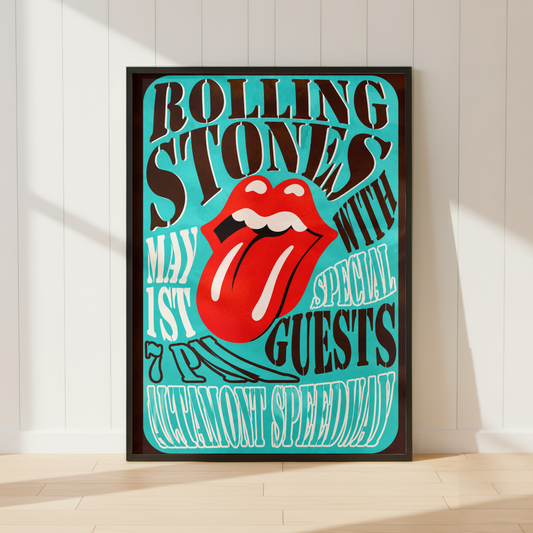 A framed poster featuring the Rolling Stones 'May 1st Special Guests Manchester Speedway' design, leaning against a white paneled wall on a light wood floor.