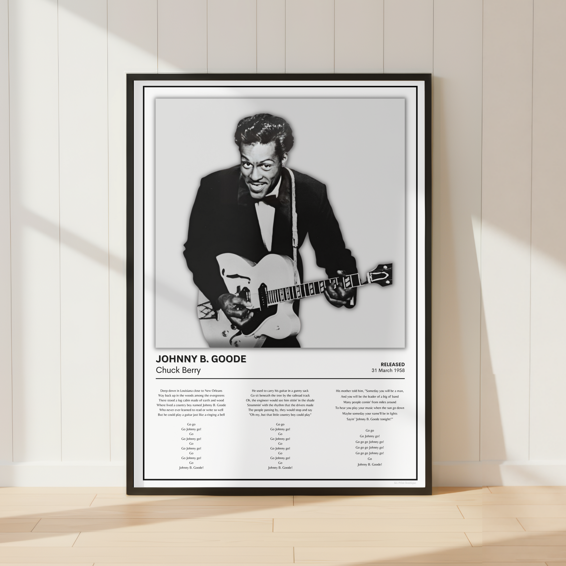 A framed black-and-white poster of jazz musician Johnny B. Goode leaning against a white paneled wall on a light wood floor, with soft window shadows cast across the scene.