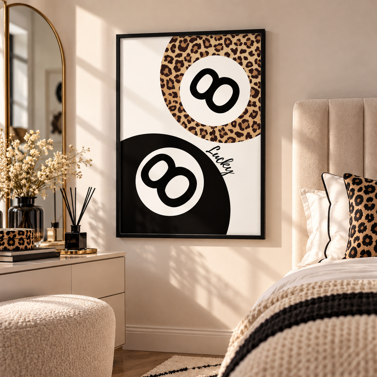 A framed wall art print featuring two black-and-white 8-ball motifs with one leopard-print circle, displayed in a styled bedroom above a bed with matching leopard-print pillows.