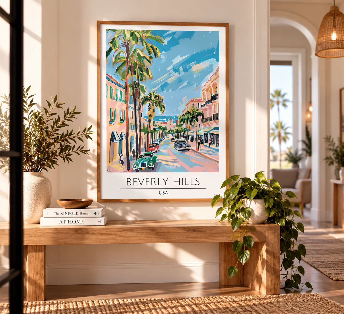 A framed art print of a colorful Beverly Hills street scene with palm trees and the text 'BEVERLY HILLS USA' at the bottom, displayed on a wooden bench in a bright, modern living room.