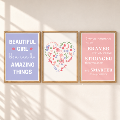 Three framed motivational wall art prints displayed side by side on a warm beige wall with soft window shadow patterns. The left print has a lavender background with white text reading 'BEAUTIFUL GIRL You can do AMAZING THINGS'.