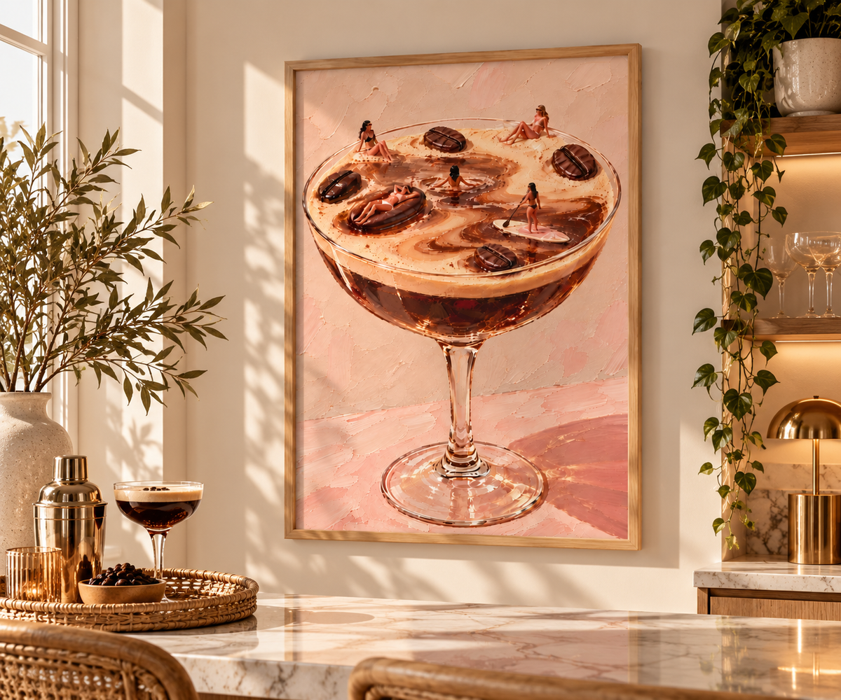 A framed art print depicting a cocktail in a coupe glass, displayed on a warm beige wall in a beautifully styled bar or kitchen setting with marble countertops, plants, and warm lighting.